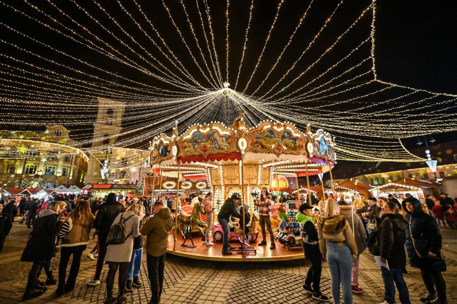 Christmas market with a carousel and string lights overhead.