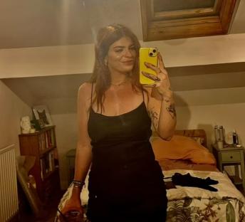 A woman in a black dress taking a selfie.