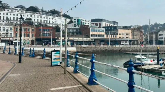 View of a UK seaside town with buildings, shops, and a marina.