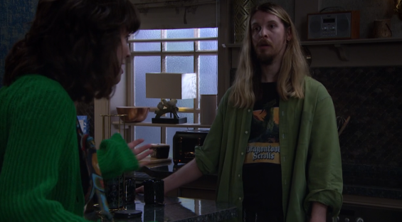 Screenshot of a man and woman talking in a kitchen.