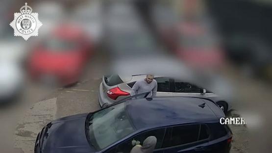 Surveillance footage of a man getting into a car.