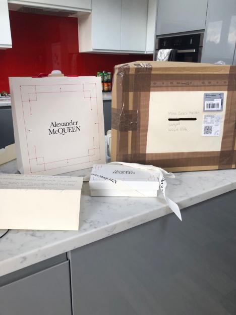 Alexander McQueen gift box and card on a counter next to a large parcel addressed to Miss Grace Hallam.
