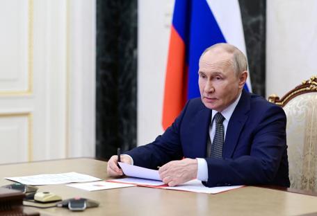 Vladimir Putin reviewing documents at a meeting.