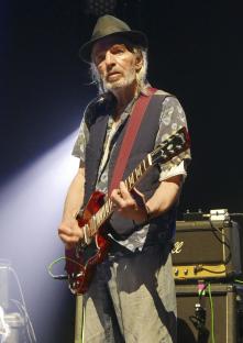 Brian James of The Damned performing on stage with a guitar.