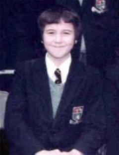 a young boy in a school uniform is smiling for the camera