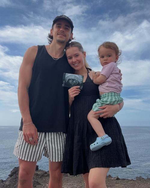 A parent's hands gently cradling their sleeping newborn on a soft white blanket.