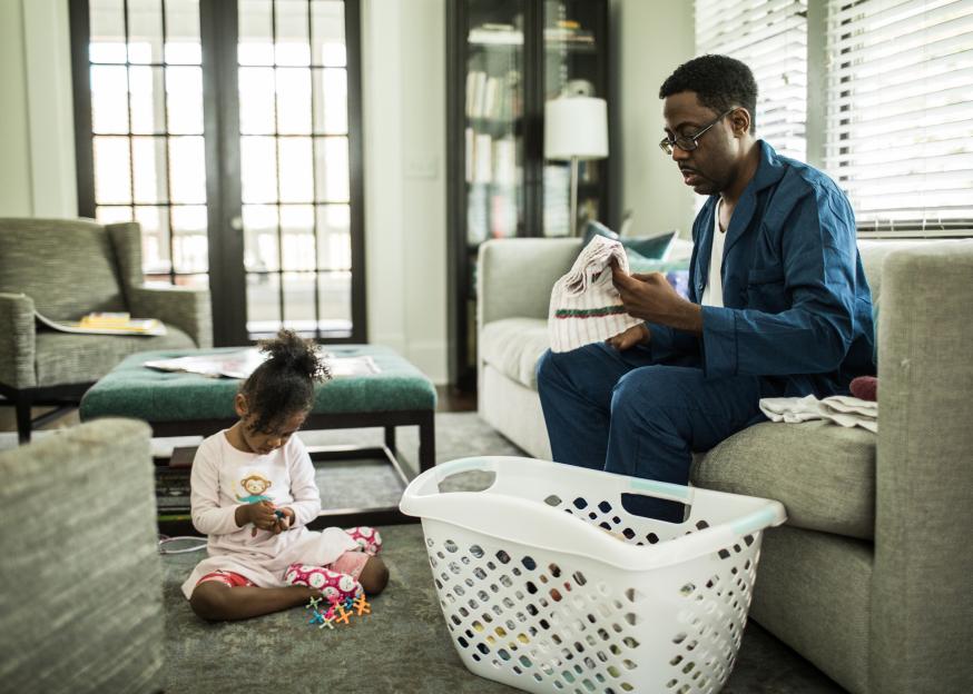 Father and daughter folding laundry at home.