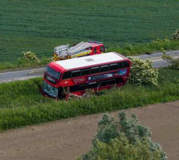 Double-decker bus in accident; emergency responders at the scene.
