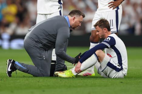 James Maddison of Tottenham Hotspur receiving medical attention on the field.