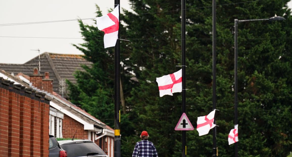 A man walks past St. George's flags on lampposts.