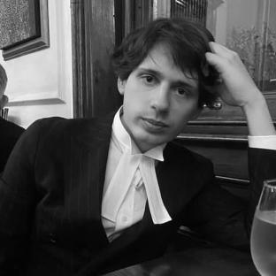 Black and white photo of a young man in a barrister's gown.
