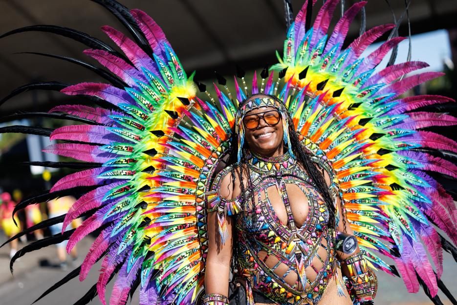 A woman in a colorful feathered costume at the Notting Hill Carnival.