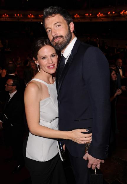Jennifer Garner in a light grey top and black skirt with Ben Affleck in a dark suit, holding a golden award.