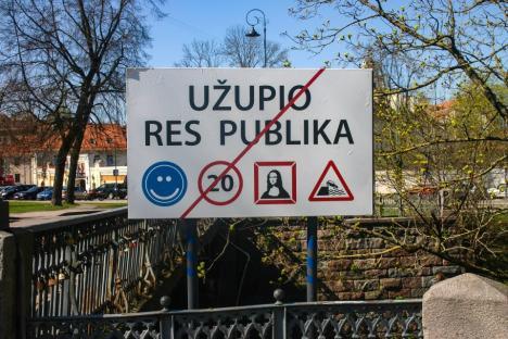 Sign indicating UÃ
¾upio Res Publika with a smiley face, a crossed-out 20 speed limit, Mona Lisa, and a downhill traffic sign.