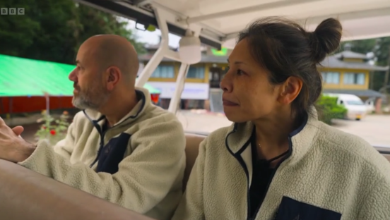 Screenshot of a man and woman sitting in a golf cart.