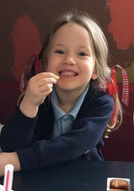 Violet-Grace smiling while holding a snack.