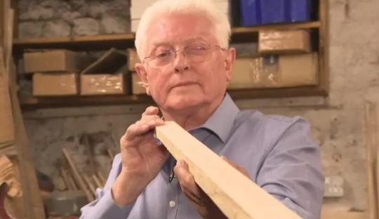 Man holding a piece of wood for a cue.