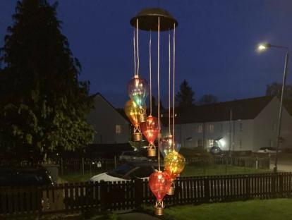 Solar-powered hot air balloon lights hanging in a garden at night.