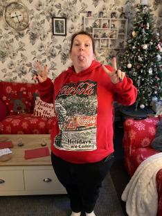 Woman in Coca-Cola sweatshirt making peace signs.