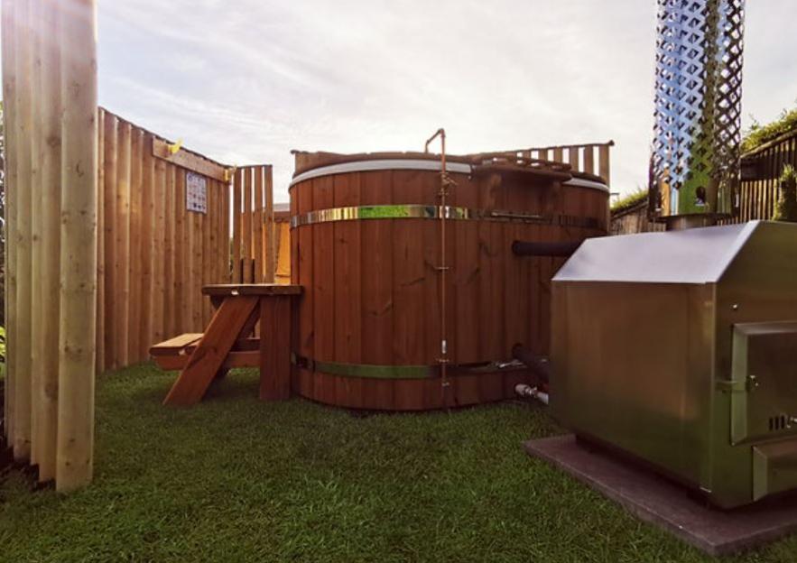 Outdoor wood-fired hot tub with privacy fence.