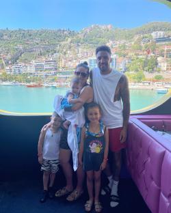 Family posing on a boat with a coastal town in the background.