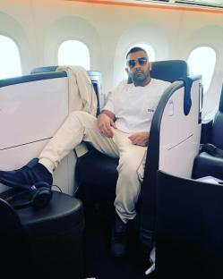 Man in sunglasses sitting in an airplane seat.