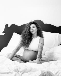 Black and white photo of a pregnant woman sitting in bed.