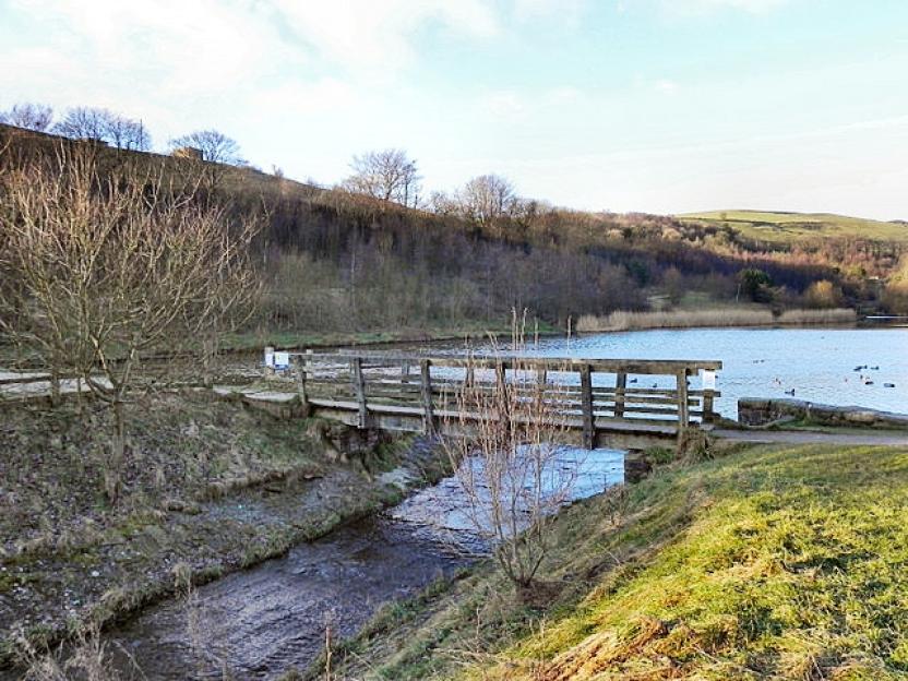 Wooden footbridge over stream near reservoir.