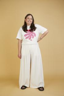Woman in white pants and shirt smiling.
