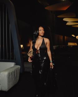 Woman in black outfit walking indoors.