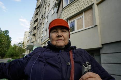 Close-up of an older woman wearing a red headband and dark jacket, holding walking poles.