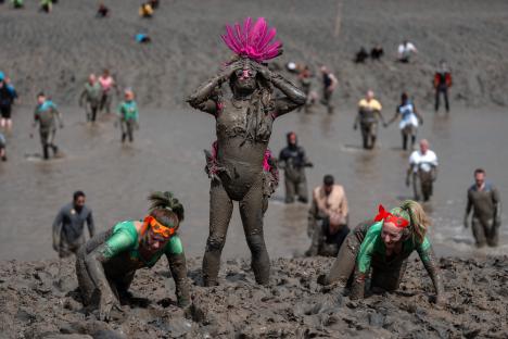 Competitors covered in mud participate in a mud race.