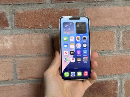 Hand holding iPhone displaying apps and weather.