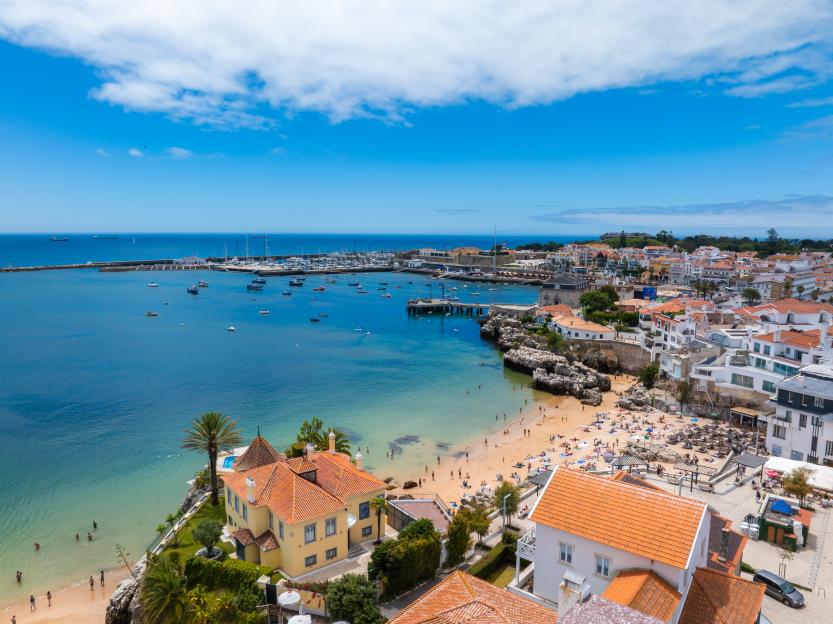 Drone aerial view of Praia da Rainha and historic city center of Cascais, Portugal.