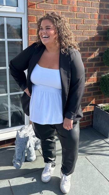 Amy Tapper smiling in a black blazer, white top, and black leather-look pants.