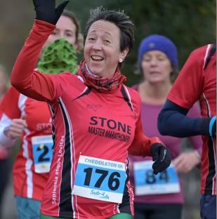 Woman in Stone Master Marathoners shirt waving at Cheddleton 10k race.