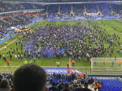 Reading fans protesting on the pitch during a soccer match.
