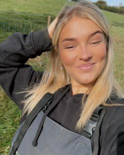 Woman with blonde hair smiling outdoors.