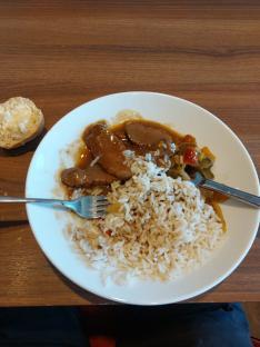 Plate of rice, meat in gravy, and vegetables.