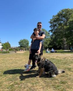 Simon Cowell with his son and dog in a park.