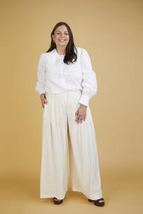 A woman wearing a white collared shirt and wide-leg pants.