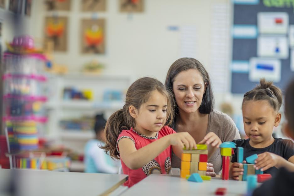 Pre-school teacher playing with girls in kindergarten