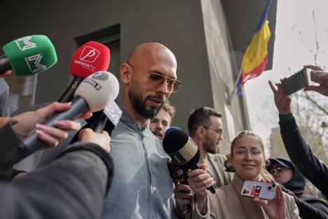 Andrew Tate speaking to reporters outside a building.