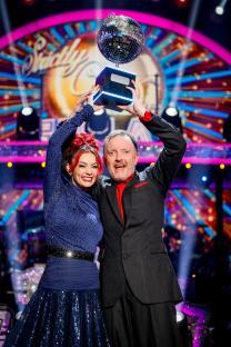 Dianne Buswell and Chris McCausland holding the Strictly Come Dancing trophy.