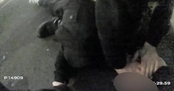 Video still of a police officer arresting a person.