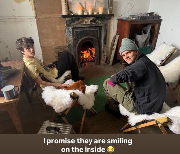Cruz and Romeo Beckham sitting by a fireplace.