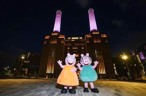 Mummy and Daddy Pig mascots in front of Battersea Power Station at night.