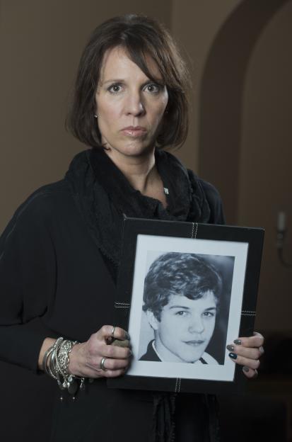 A woman holds a framed photo of her son.