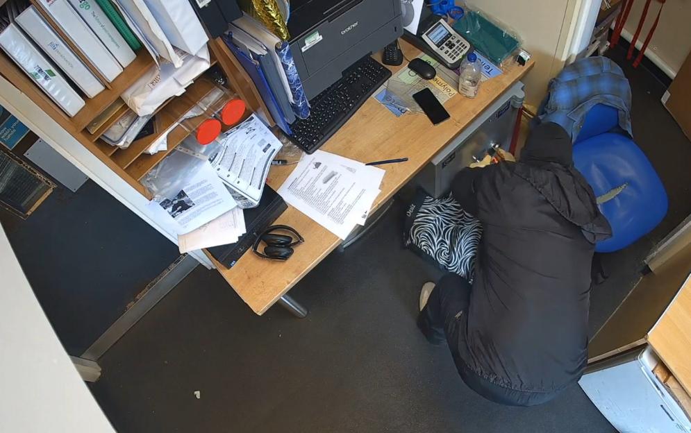 Surveillance image of a person attempting to rob a safe.