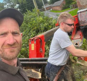 Two men using a wood chipper.